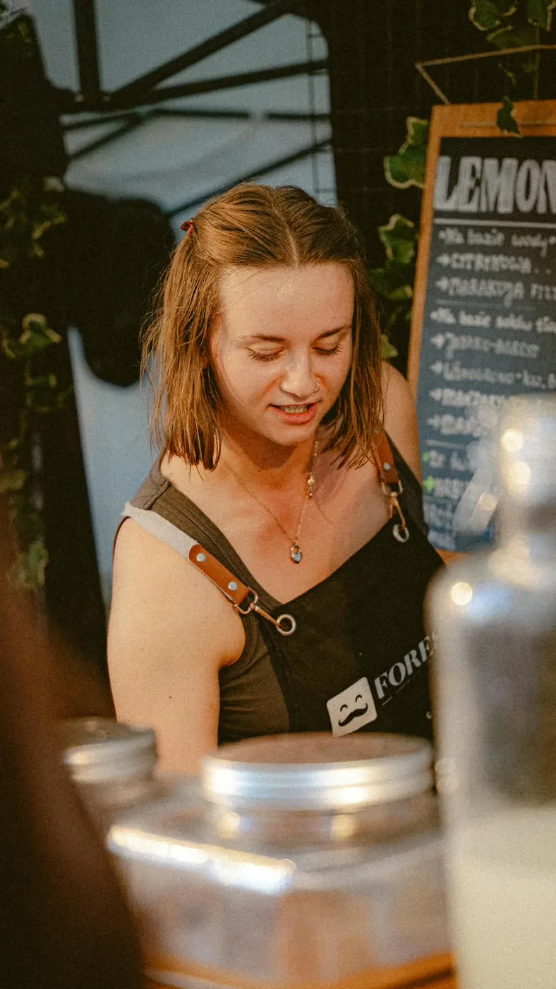 Barmanka w fartuchu Forest przy słojach z lemoniadą