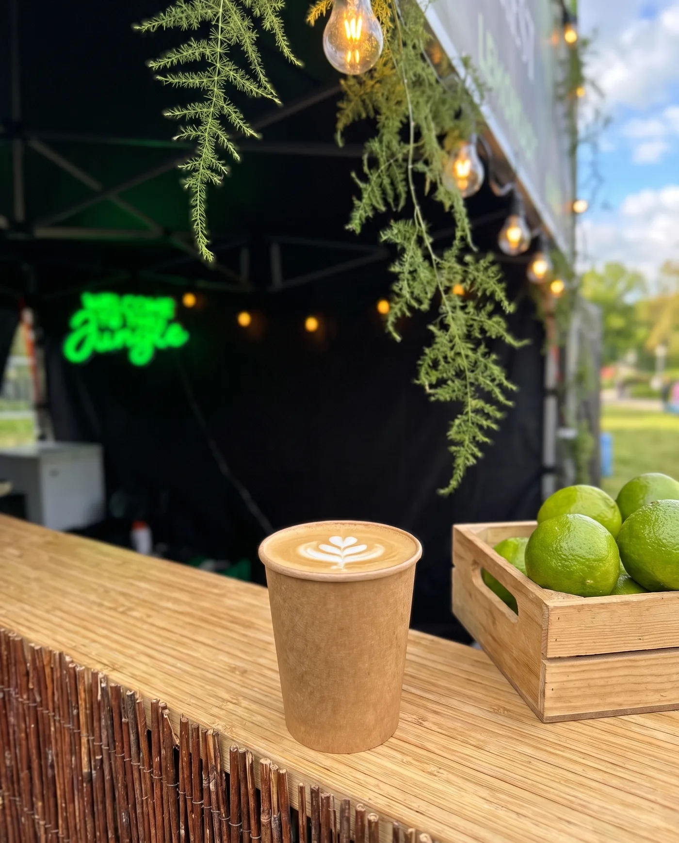 Flat white w papierowym kubku obok skrzynki limonek