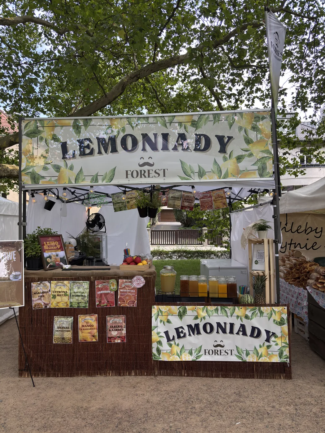 Stoisko lemoniad Forest pod platanem, słoje z lemoniadą na ladzie
